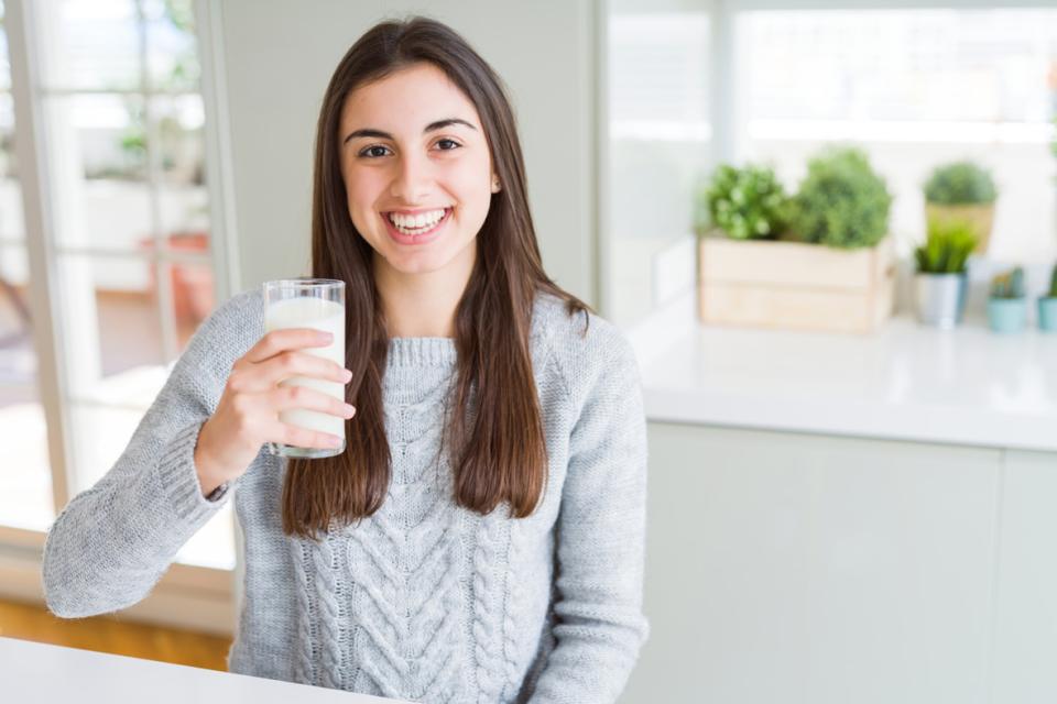 Young woman holding a glass of milk and smiling