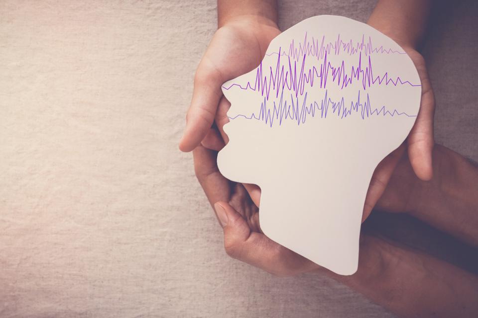 Mains d'adultes tenant un cerveau d'encéphalographie en papier découpé