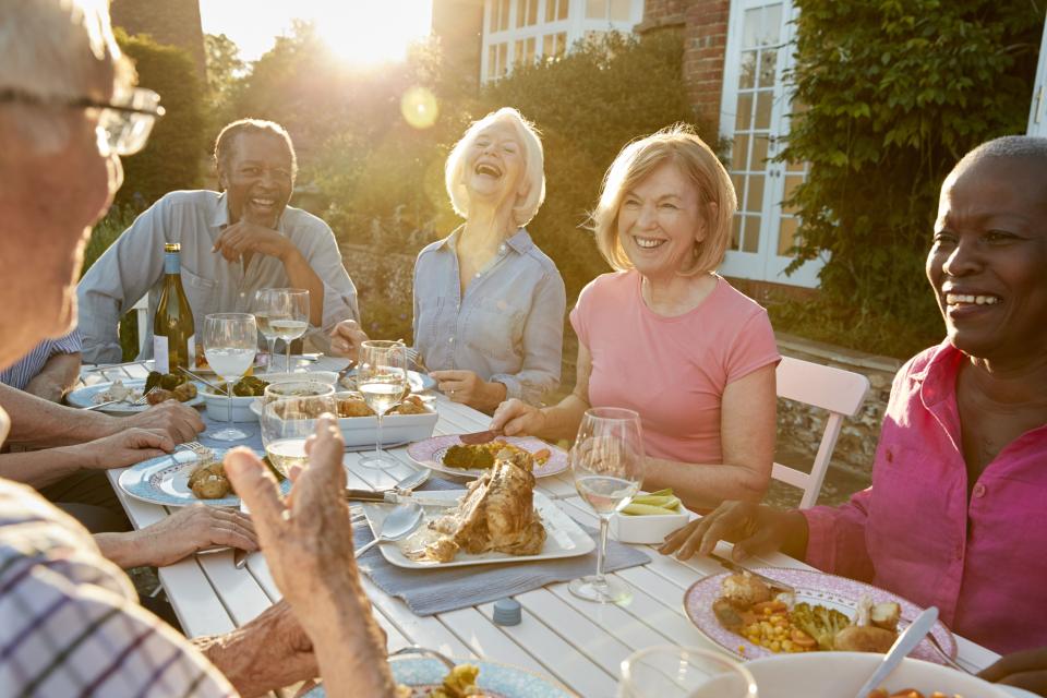 Group de gens plus agés qui mangent autour d`une table dehors