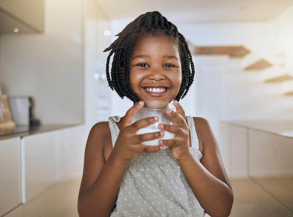 Young girl smiling and holding a glass of milk