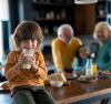 little boy sitting on the counter holding a glass of milk